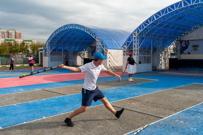 Спортсмен из Германии кидает биту на соревнованиях по городошному спорту в Подольске