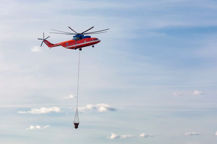 Пожарный вертолет набирает воду в Москве-реке для тушения возгорания