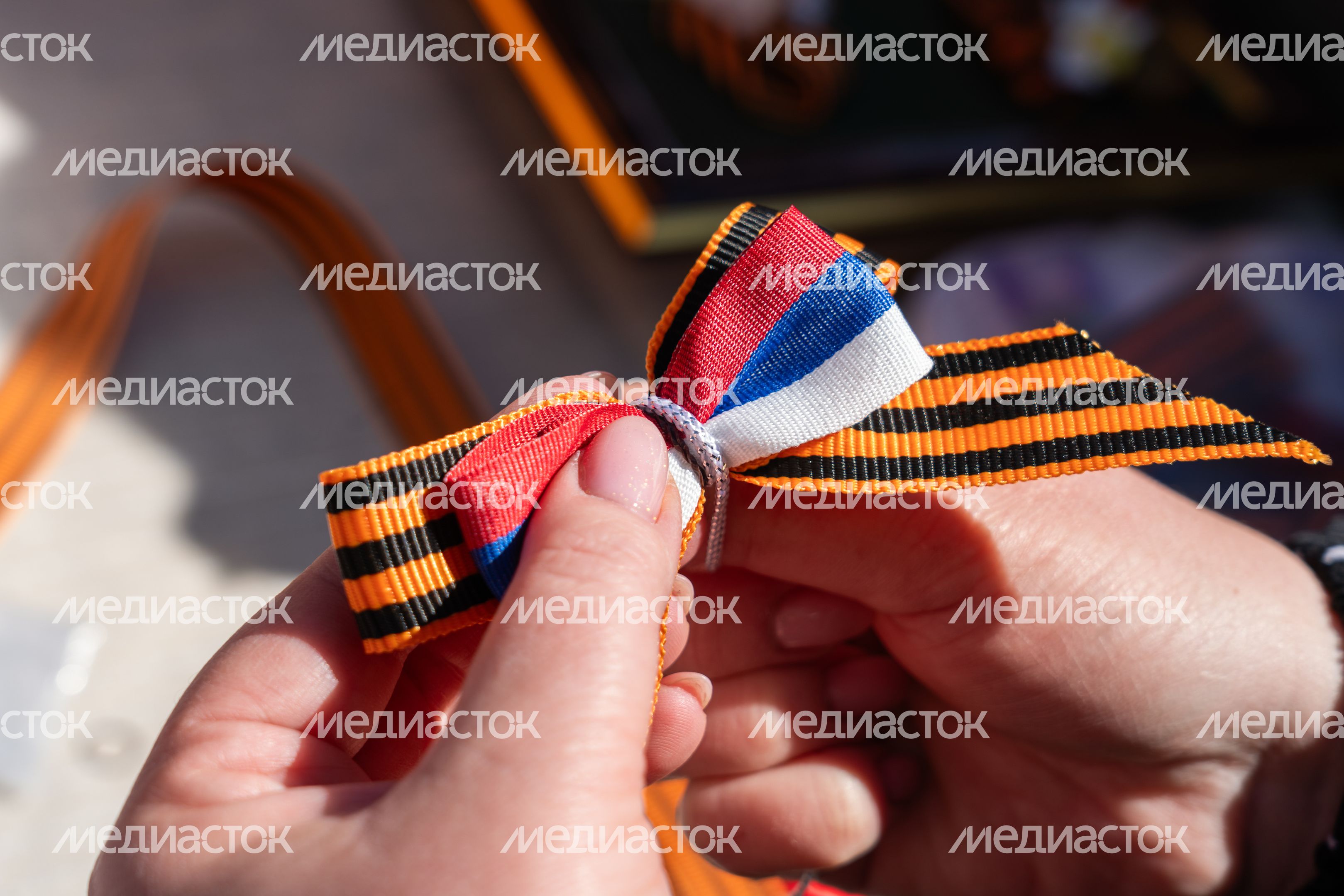 Георгиевская лента связана в один значок с лентой в цветах российского флага Георгиевская лента связана в один значок с лентой в цветах российского флага