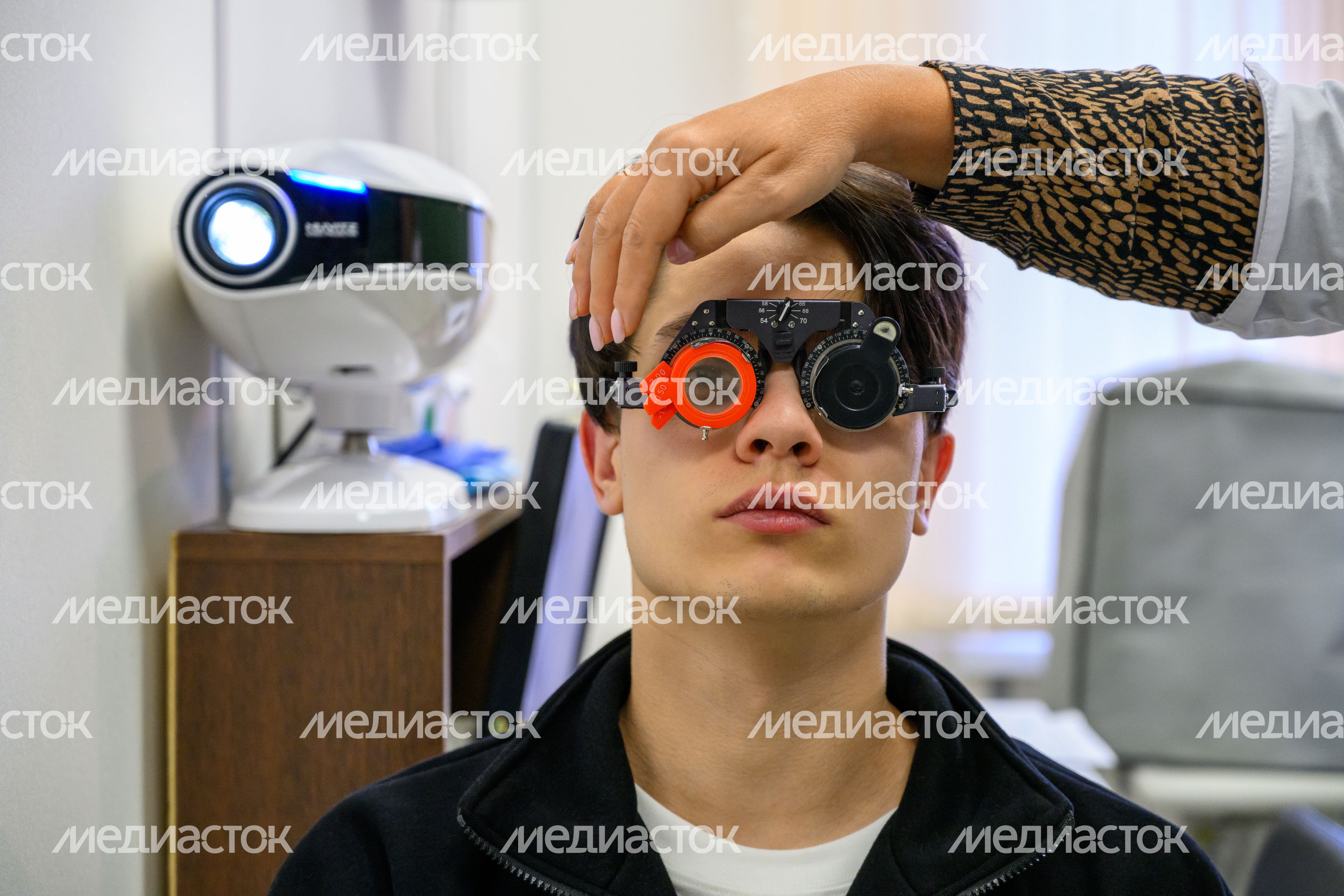 Врач-офтальмолог осматривает призывника на медкомиссии в военкомате