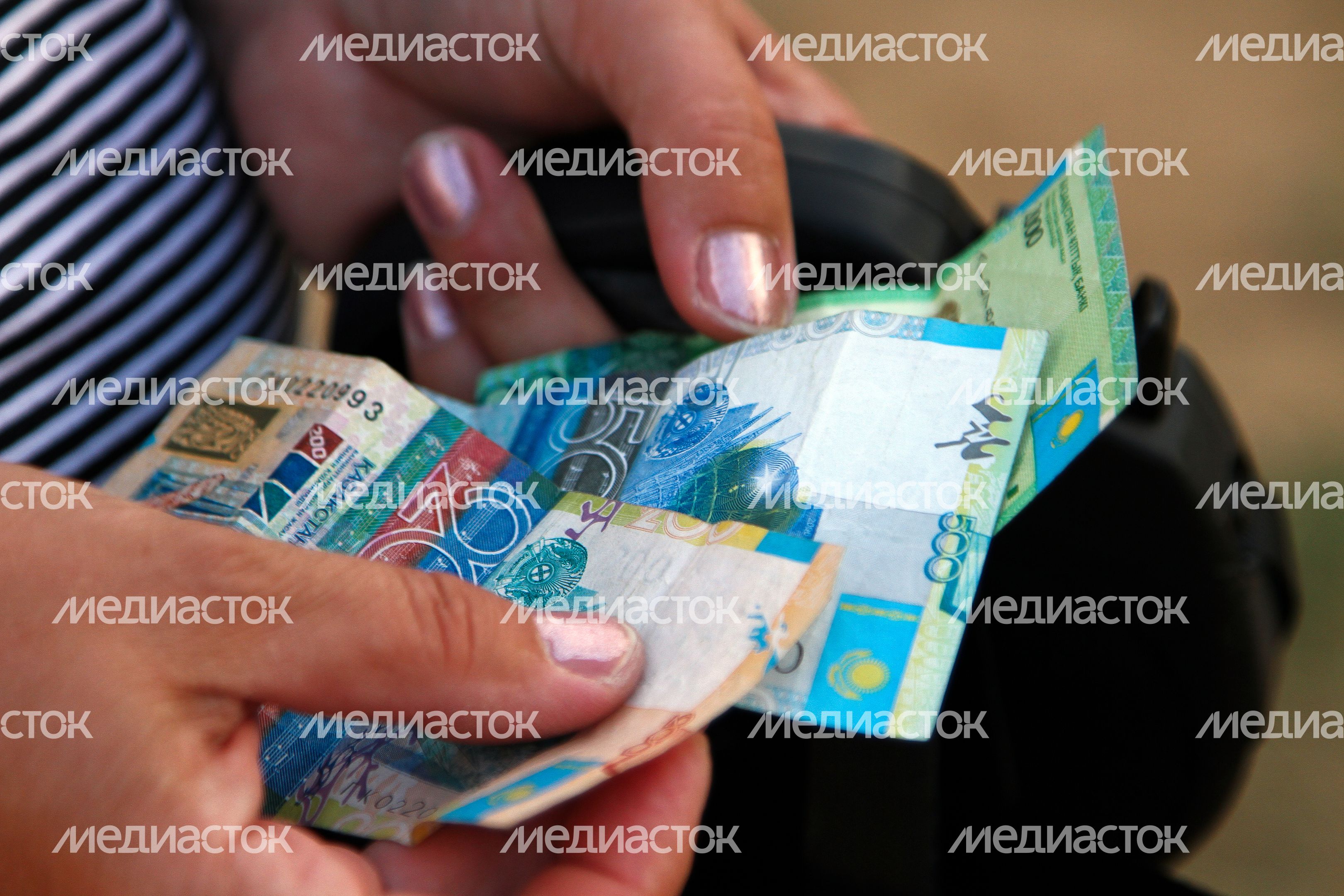 Уроженка Казахстана держит тенге Уроженка Казахстана держит тенге