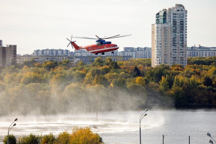 Пожарный вертолет набирает воду в Москве-реке для тушения возгорания