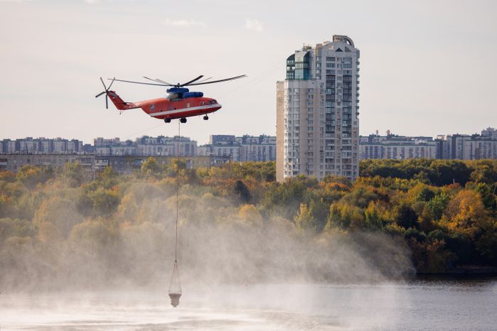 Пожарный вертолет набирает воду в Москве-реке для тушения возгорания