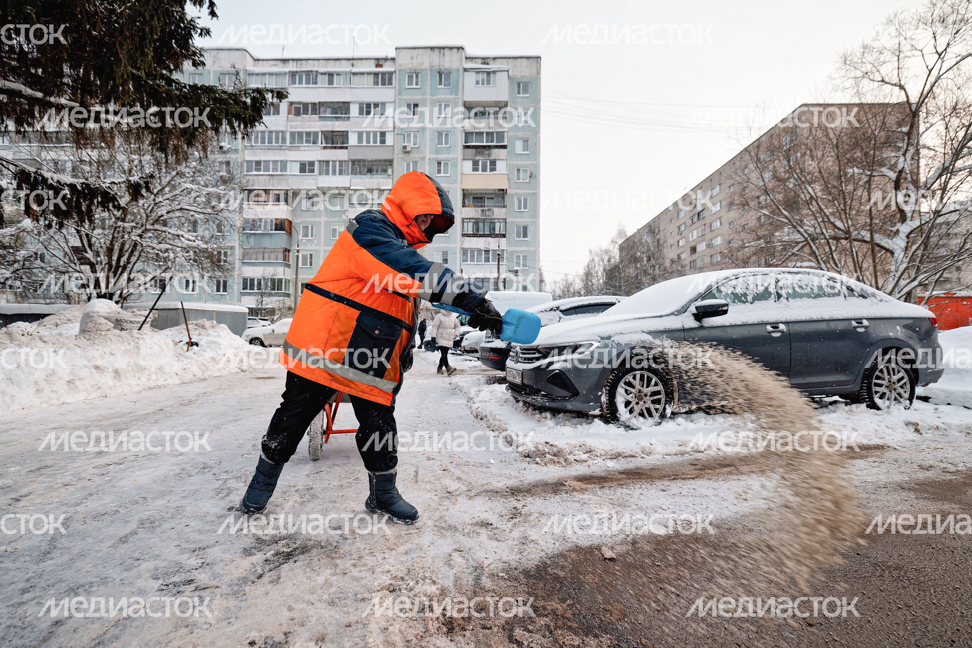 Дворник посыпает дорожку противогололедной смесью после уборки снега в поселке Большие Вяземы Одинцовского округа Дворник посыпает дорожку противогололедной смесью после уборки снега в поселке Большие Вяземы Одинцовского округа