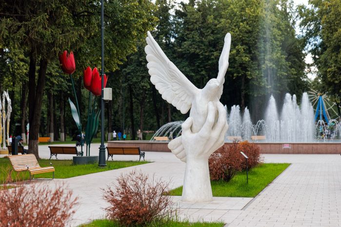 Жанровая скульптура «Голубь в руке» в парке Мира в Коломне летом
