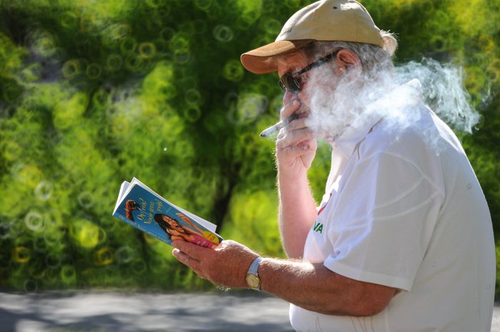 Мужчина курит сигару и читает книгу