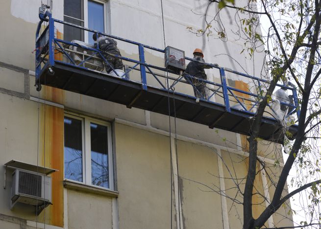 Коммунальная служба ремонтирует фасад жилого дома