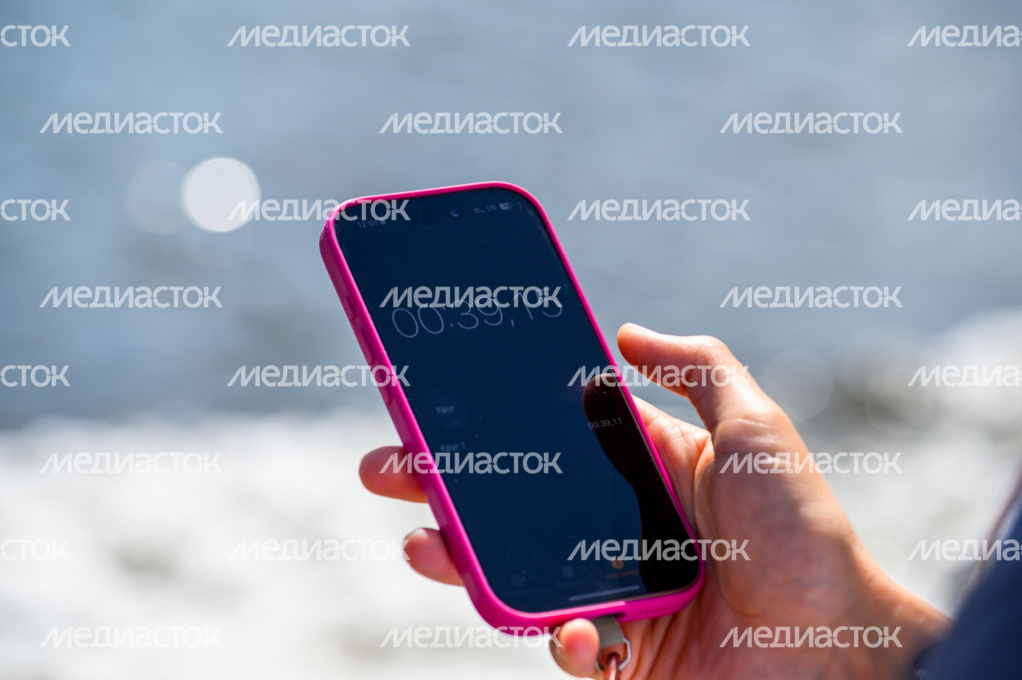 Смартфон с секундомером в руке судьи соревнований Смартфон с секундомером в руке судьи соревнований