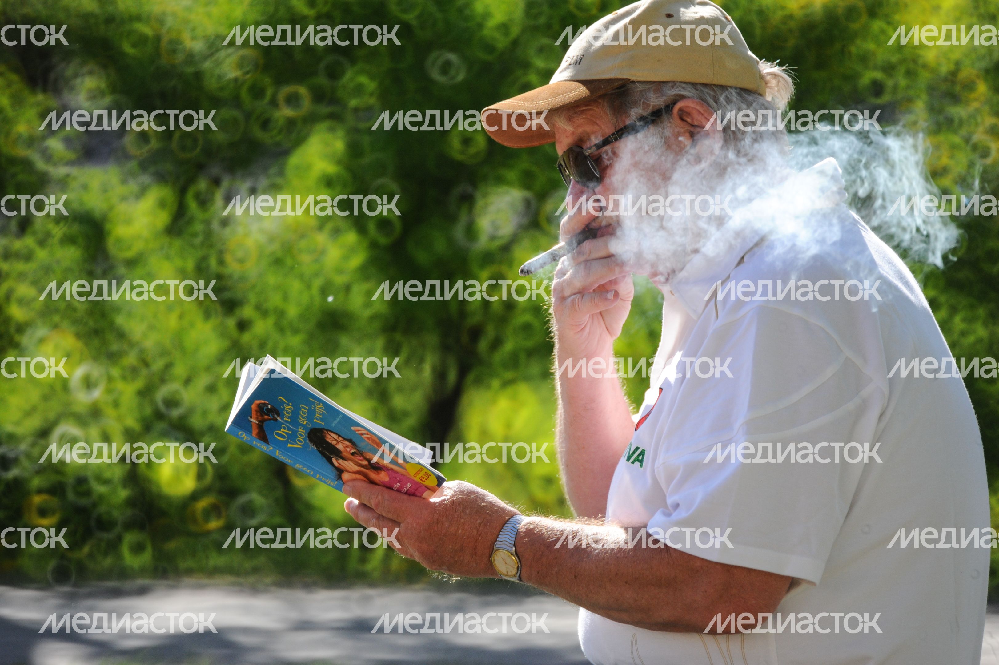 Мужчина курит сигару и читает книгу Мужчина курит сигару и читает книгу