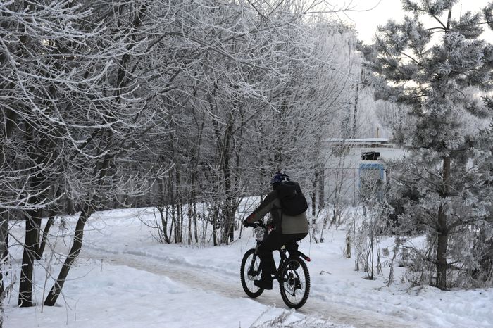 Мужчина едет на велосипеде зимой в Троицке