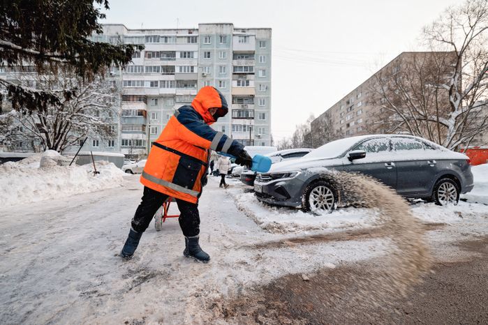 Дворник посыпает дорожку противогололедной смесью после уборки снега в поселке Большие Вяземы Одинцовского округа