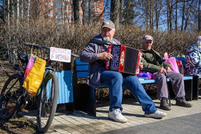 Мужчина играет на баяне в парке Мира города Мытищи